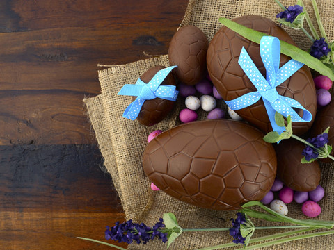 Happy Easter chocolate Easter eggs on dark wood country style table background.